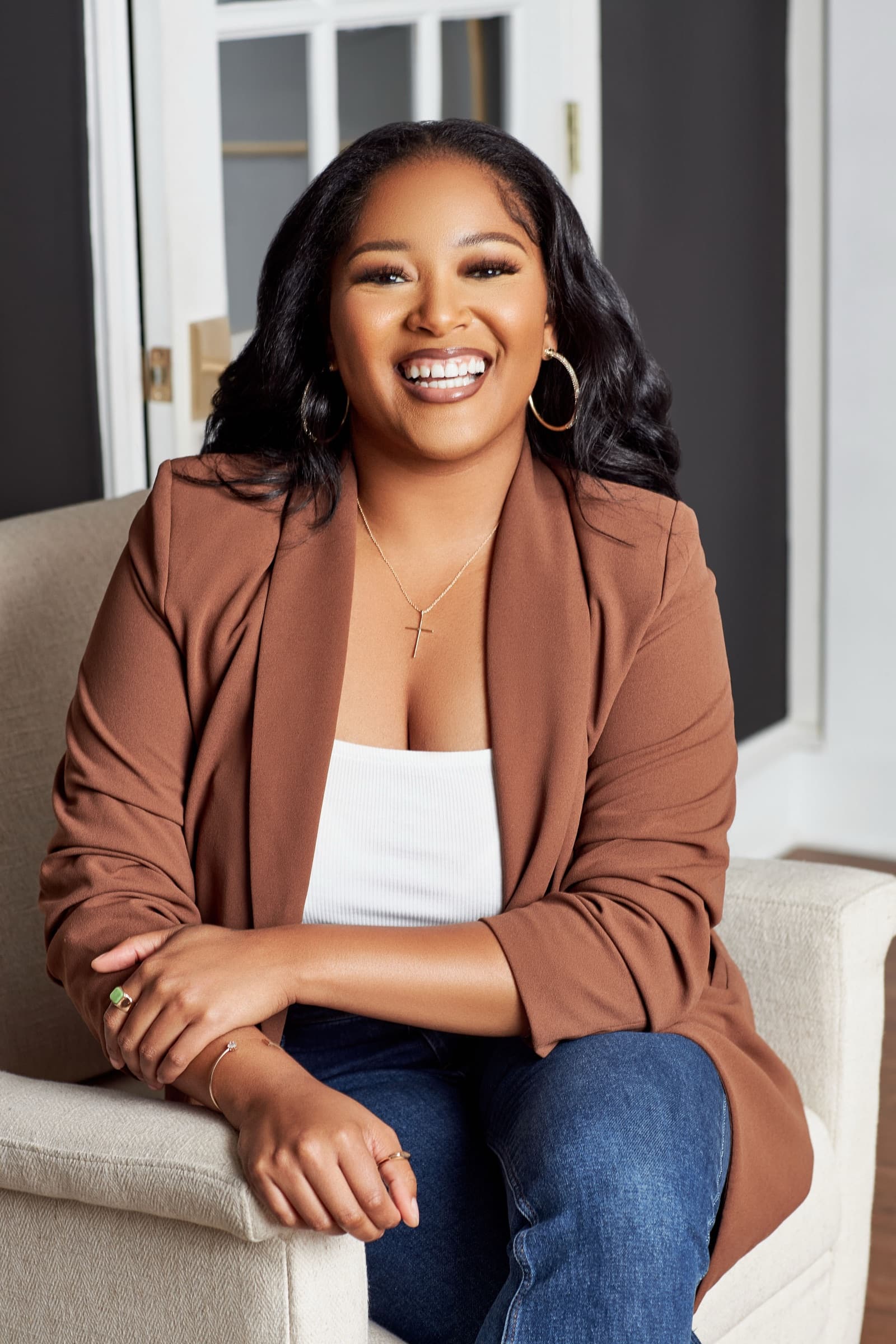 Porschia Wimbush seated, in a warm blazer against a charcoal wall